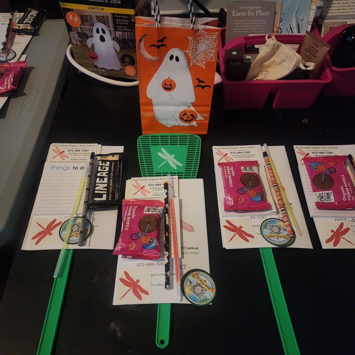 Goodie bag contents laid out on a table, including organic snack samples, a Sweeter Things LLC magnet, and brand partner materials