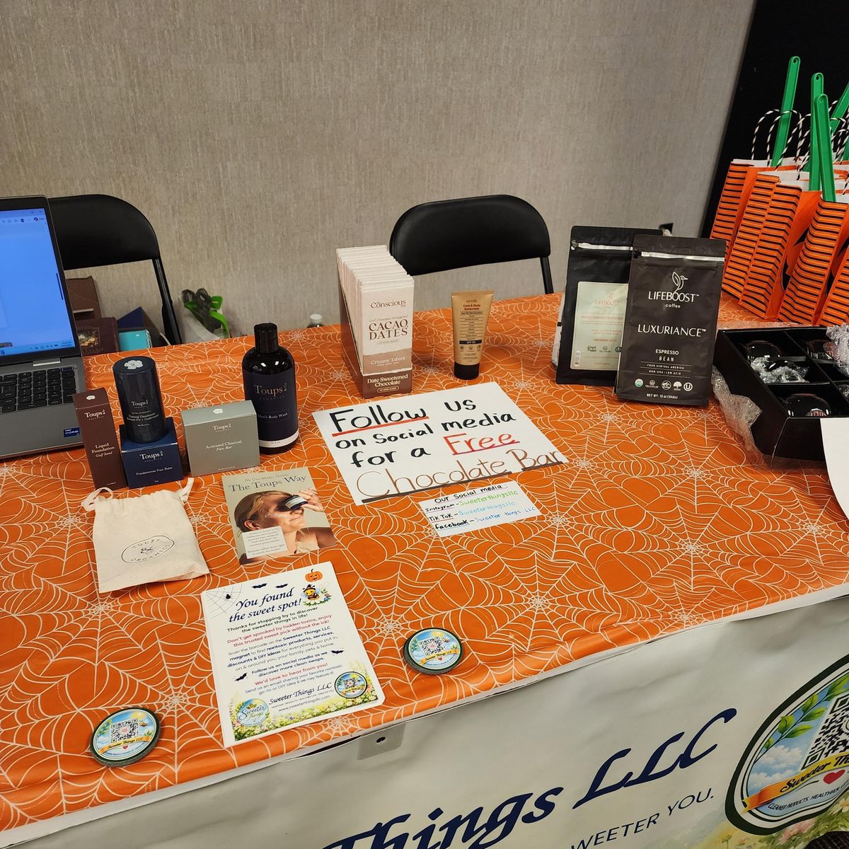 Table at the Sweeter Things LLC booth with clean skin care products, coffee, and chocolate bars from trusted brands